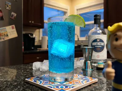 My Wasteland Glow — electric blue Nuka-Cola Quantum on a patterned tile trivet, Vault Boy bobblehead at the edge