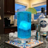 My Wasteland Glow — electric blue Nuka-Cola Quantum on a patterned tile trivet, Vault Boy bobblehead at the edge