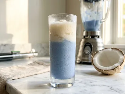 My Binary Sunset — frozen blue-and-cream layered cocktail, Luke's lightsaber hilt at the edge of the frame